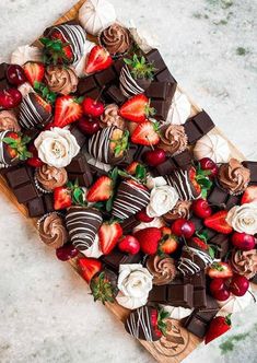 strawberries, chocolate and flowers arranged on a board