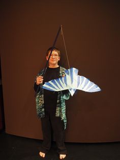 a woman holding a kite while standing in front of a brown wall and black floor