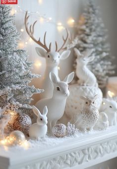 white christmas decorations with deer and rabbits on the mantel in front of lit trees