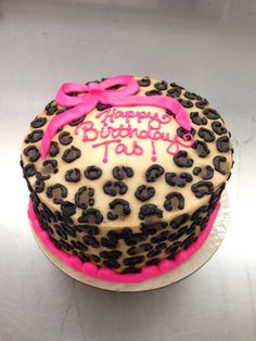 a birthday cake decorated with leopard print and pink ribbon