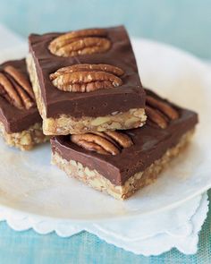 three pieces of pecan bar on a white plate with a blue table cloth behind it