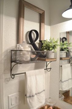 a bathroom sink with two towels hanging on the wall and some plants in baskets above it