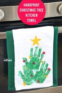 the handprint christmas tree towel is hanging on the oven door and it's green