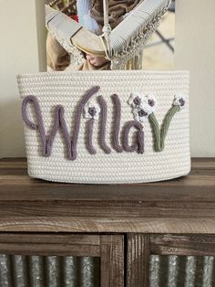 a white basket with the word willow on it sitting on top of a wooden cabinet