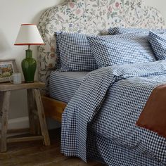 a bed with blue and white checkered bedspread next to a night stand