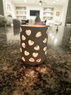 a candle holder with hearts on it sitting on a counter in front of a living room