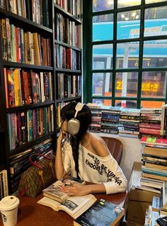 a woman sitting at a table in front of a bookshelf filled with books