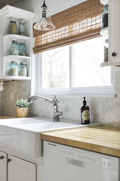 a kitchen with white cabinets and wooden counter tops, an open window above the sink