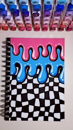 a spiral notebook covered in lots of different colored liquid drops on top of each other