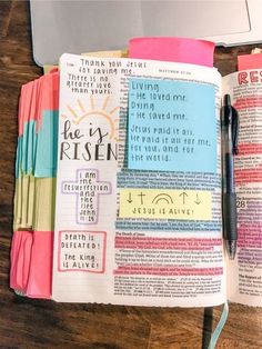 an open bible on a wooden table with a pen