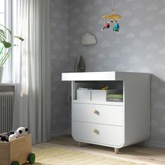 a baby's room with a white dresser and wallpaper