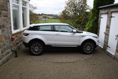 a white range rover parked in front of a house