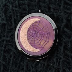 a purple compact with a spider web on the side and a half moon in the middle