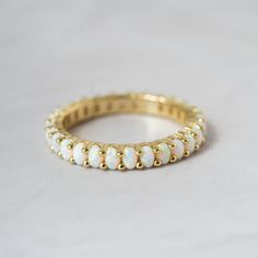 a gold ring with white opal beads on the inside and outside, sitting on a plain surface