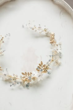 a close up of a white plate with a gold and silver head piece on it