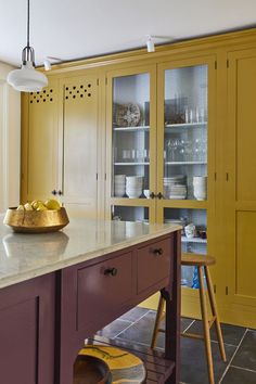 a kitchen with yellow cabinets and marble counter tops