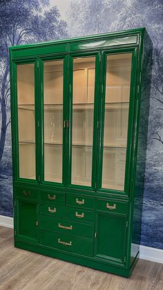 a green china cabinet with glass doors and drawers