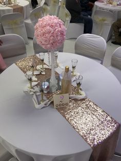 a white table topped with a vase filled with pink flowers