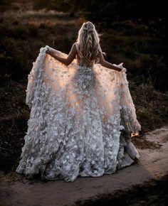 a woman in a white dress is sitting on the ground with her back turned to the camera