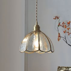 a light fixture hanging from a ceiling in a room with white walls and flowers on the wall