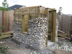 a building made out of rocks and wood with a wooden fence in the back ground