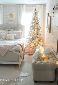 a bedroom decorated for christmas with a bed, couch and tree in the corner by the window