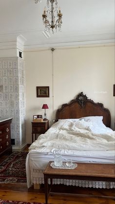 a bed sitting in the middle of a bedroom next to a dresser and table with a lamp on top of it