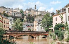 a bridge over a river with buildings on the hillside in the background and people walking across it