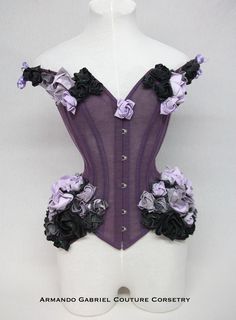 Twilight Rose is an enchanting, off the shoulder corset. Delicate, yet sturdy, it is supported by spiral and flat steel bones. The front has a steel busk, whilst the back laces permit size adjustments. The back has a modesty panel. The corset is made from strong mesh, covered by several layers of lilac and purple tulle.  Individually, hand folded and painted, cotton origami roses are applied on the hip, bust and shoulder areas.  This item is ideal for the following natural measurements: Waist: 6 Purple Gothic Corset For Costume Party, Gothic Purple Corset For Costume Party, Purple Corset Dress With Fitted Bodice, Elegant Fitted Purple Corset, Purple Overbust Corset Dress For Costume Party, Gothic Fitted Purple Corset Dress, Gothic Purple Corset With Corset Back, Purple Corset Back Dress, Fitted Gothic Purple Corset Dress