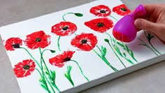 someone is painting red flowers on white paper