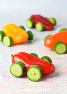 small toy cars made out of peppers and cucumbers on a white tablecloth