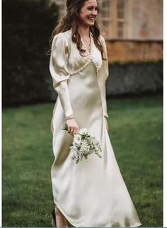 a woman in a long white dress is walking through the grass with her hand on her hip