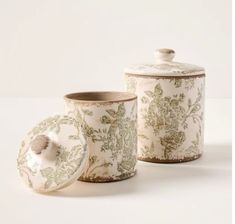 three ceramic containers with lids and designs on them, one has a flowered design