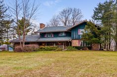 a large green house sitting on top of a lush green field next to tall trees