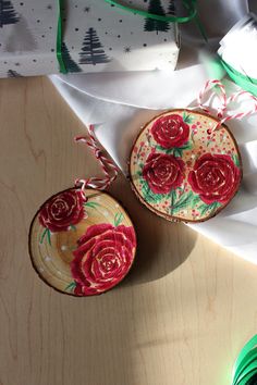 two red roses are sitting on top of a wooden plate and some white paper with green string