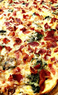 a pizza with bacon, spinach and cheese on it sitting on a wooden table