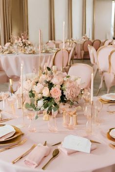 the table is set with pink flowers and gold place settings for an elegant wedding reception