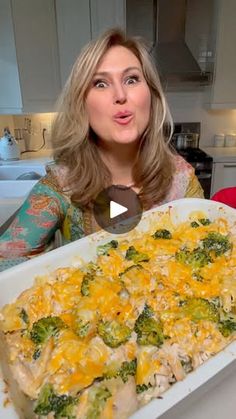 a woman is holding up a casserole dish with broccoli and cheese