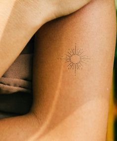 a woman's arm with a tattoo on it that has a sunburst in the middle