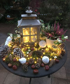 a table topped with lots of pine cones and christmas lights next to a small lantern