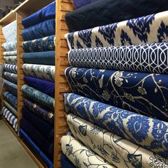 stacks of blue and white fabrics on display in a store or showroom with wooden shelving