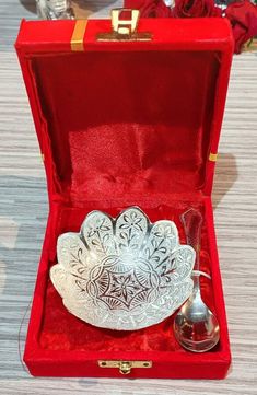 an ornate silver bowl in a red velvet case with a spoon and cup inside it