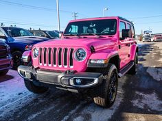 a bright pink jeep is parked in a parking lot with other cars and trucks behind it