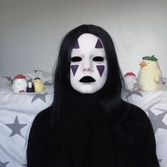 a person wearing a white mask with purple stars on the face and black long hair