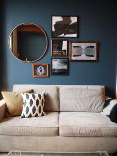 a living room with blue walls and pictures on the wall above the couch, along with a coffee table