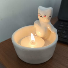 a white cat candle holder sitting on top of a wooden table