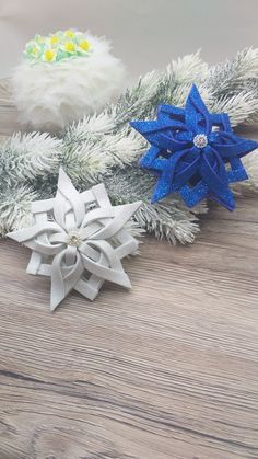 three snowflakes are sitting on a wooden table next to pine cones and branches