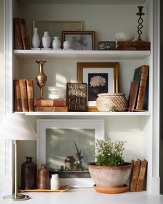 a white shelf filled with lots of books and vases on top of each other