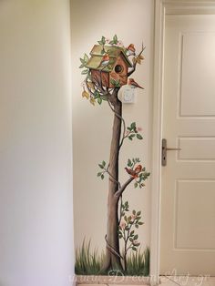 a wall with a tree and birdhouse painted on it's side, next to a door