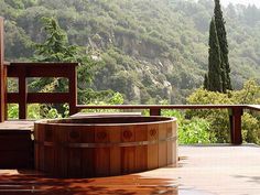 a wooden hot tub sitting on top of a patio next to a table and chairs